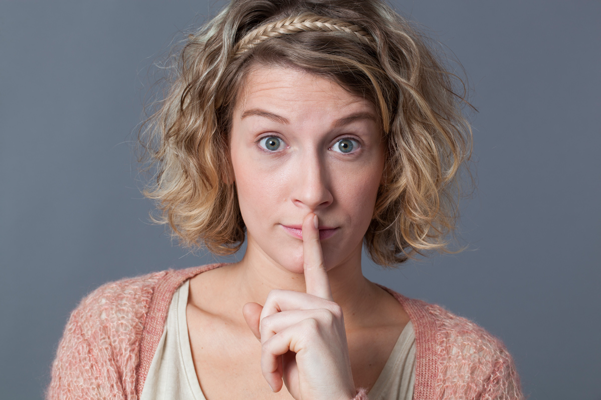 Frau legt Finger an die Lippen Frau legt Finger an die Lippen