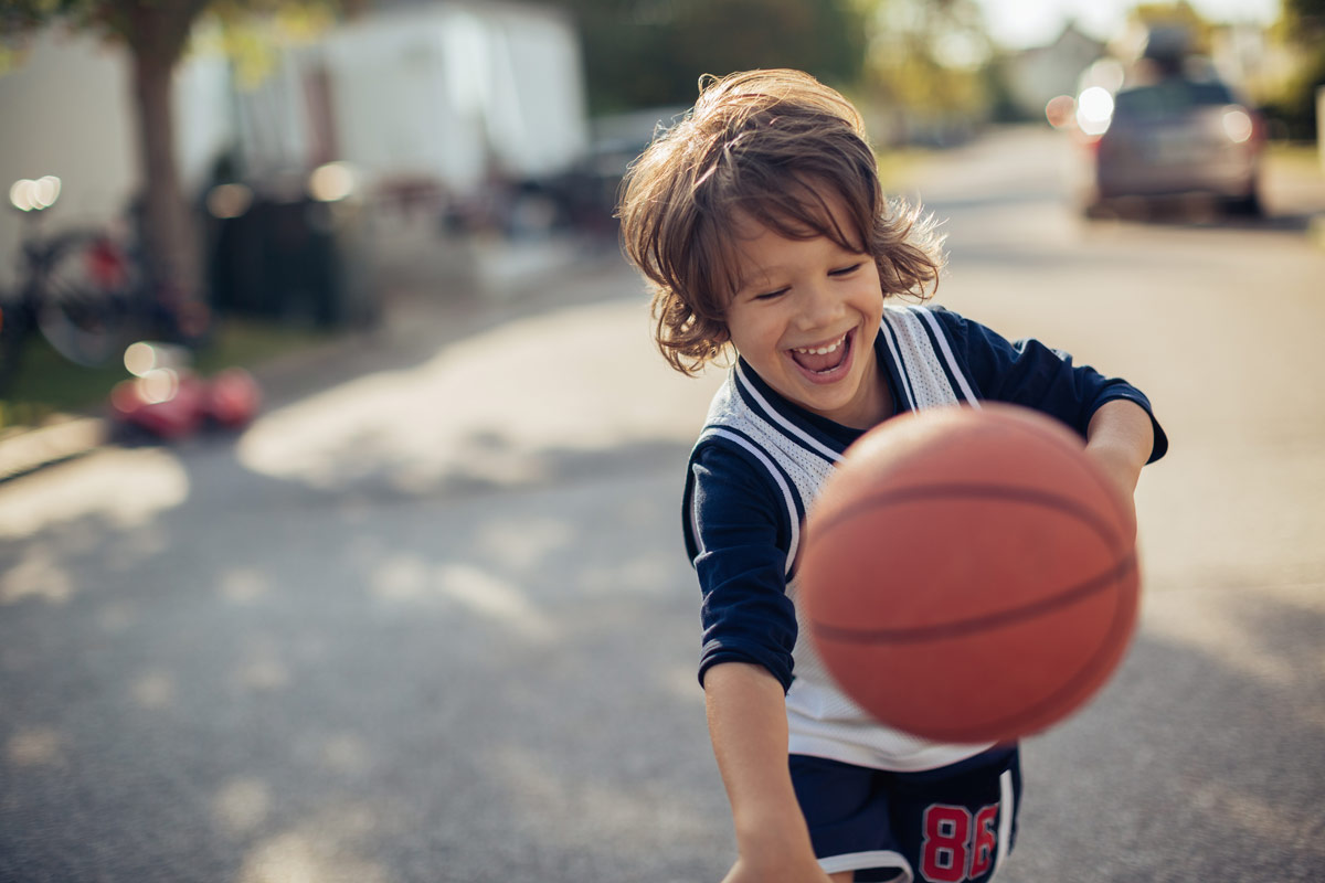 Junge spielt Baskettball auf der Straße Junge spielt Baskettball auf der Straße