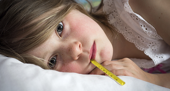 Mädchen liegt mit Fieber im Bett