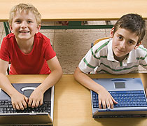 Zwei Jungen sitzen vor Laptops