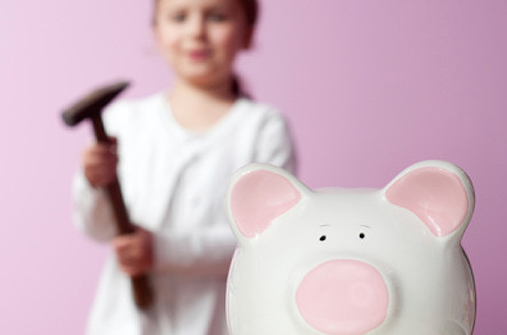 Kind mit Hammer hinter Sparschwein