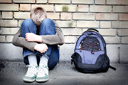 trauriger Junge lehnt an Wand
