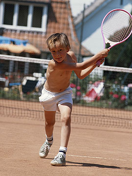Junge schlägt nach dem Tennisball