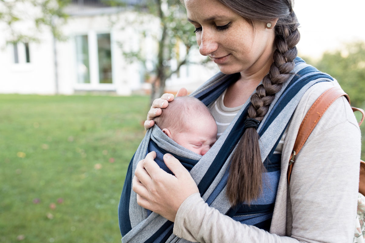 Mutter kuschelt mit Baby im Tragetuch