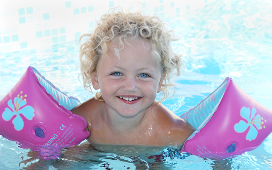 Schwimmhilfen: Mädchen mit Schwimmfkügeln im Pool