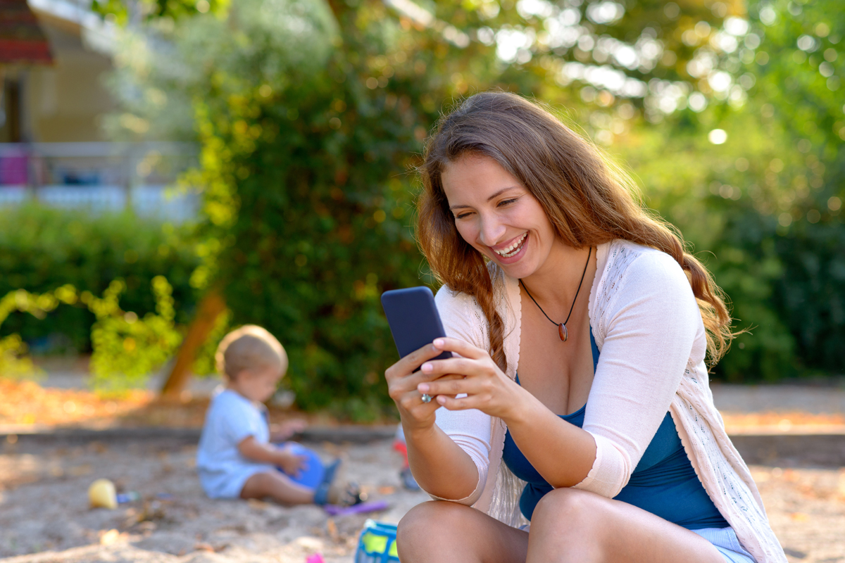 Mutter mit Smartphone auf dem Spielplatz