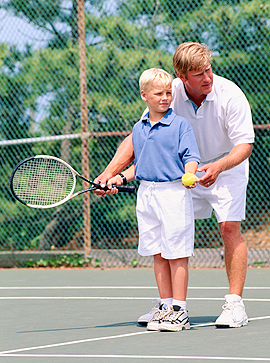 Tennislehrer trainiert kleinen Jungen