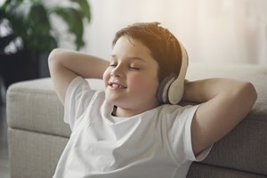 Junge sitzt entspannt mit Kopfhörern.