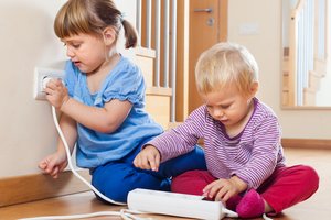 Kinder spielen mit einer Steckdose