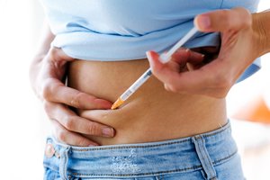 Orgalutran: Frau setzt sich Spritze in den Bauch