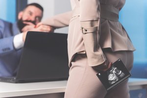 Arbeitnehmerin steht mit Ultraschallbild vor ihrem Chef