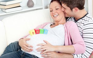 Schwangere liegt in den Armen ihres Partners