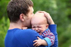 Vater tröstet Baby mit Bauchschmerzen