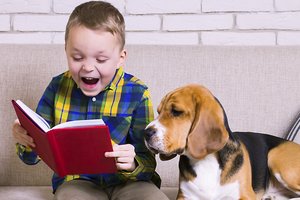 ein Junge liest einem Hund etwas vor