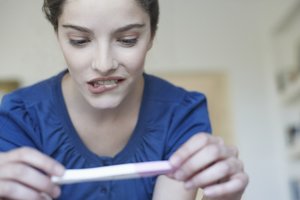 Eisprung ohne Periode: Frau blickt auf Schwangerschaftstest
